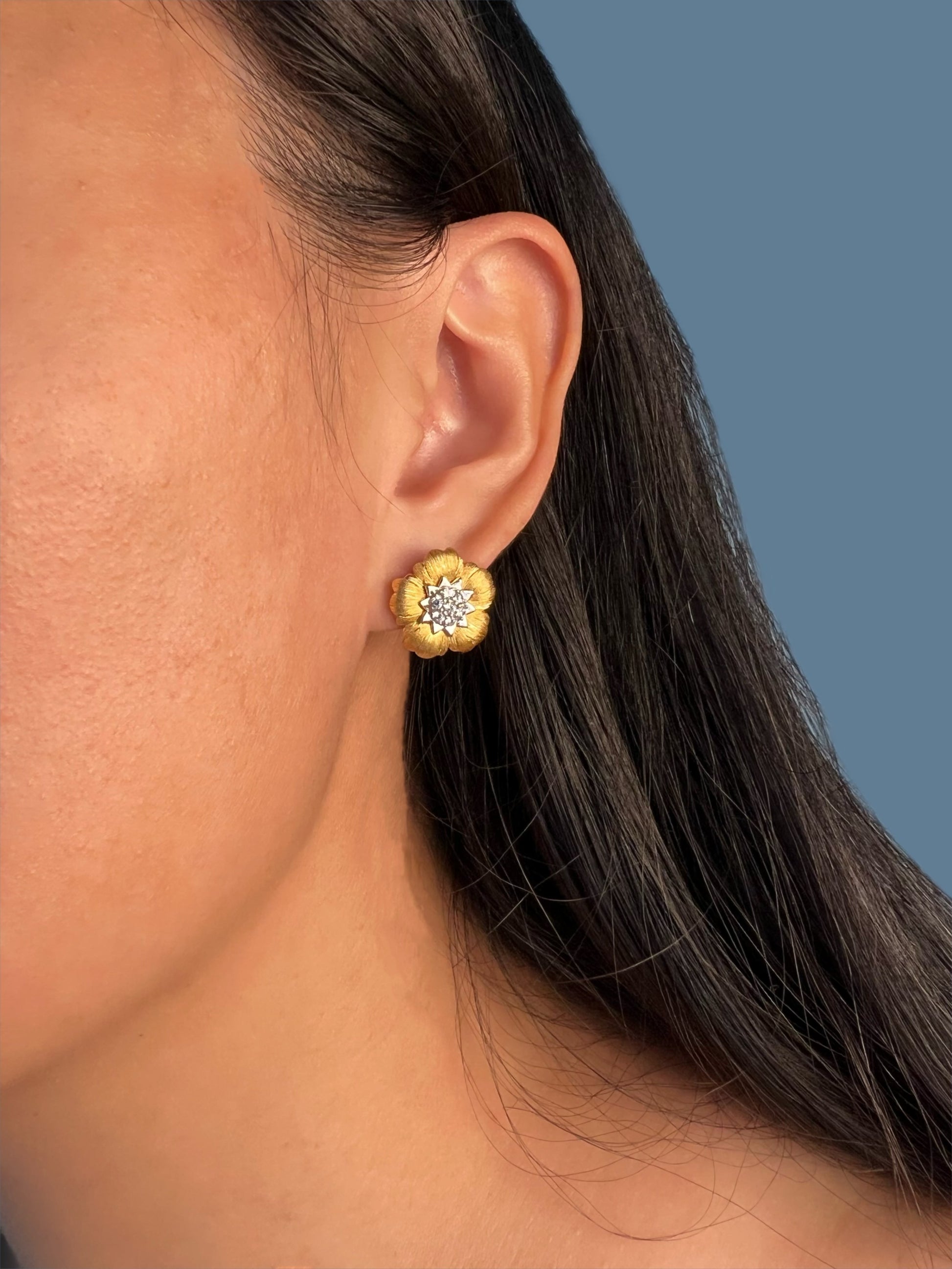 Elegant model wearing the Gold Tone Blossom Earrings featuring a faux diamond center and silver accents.