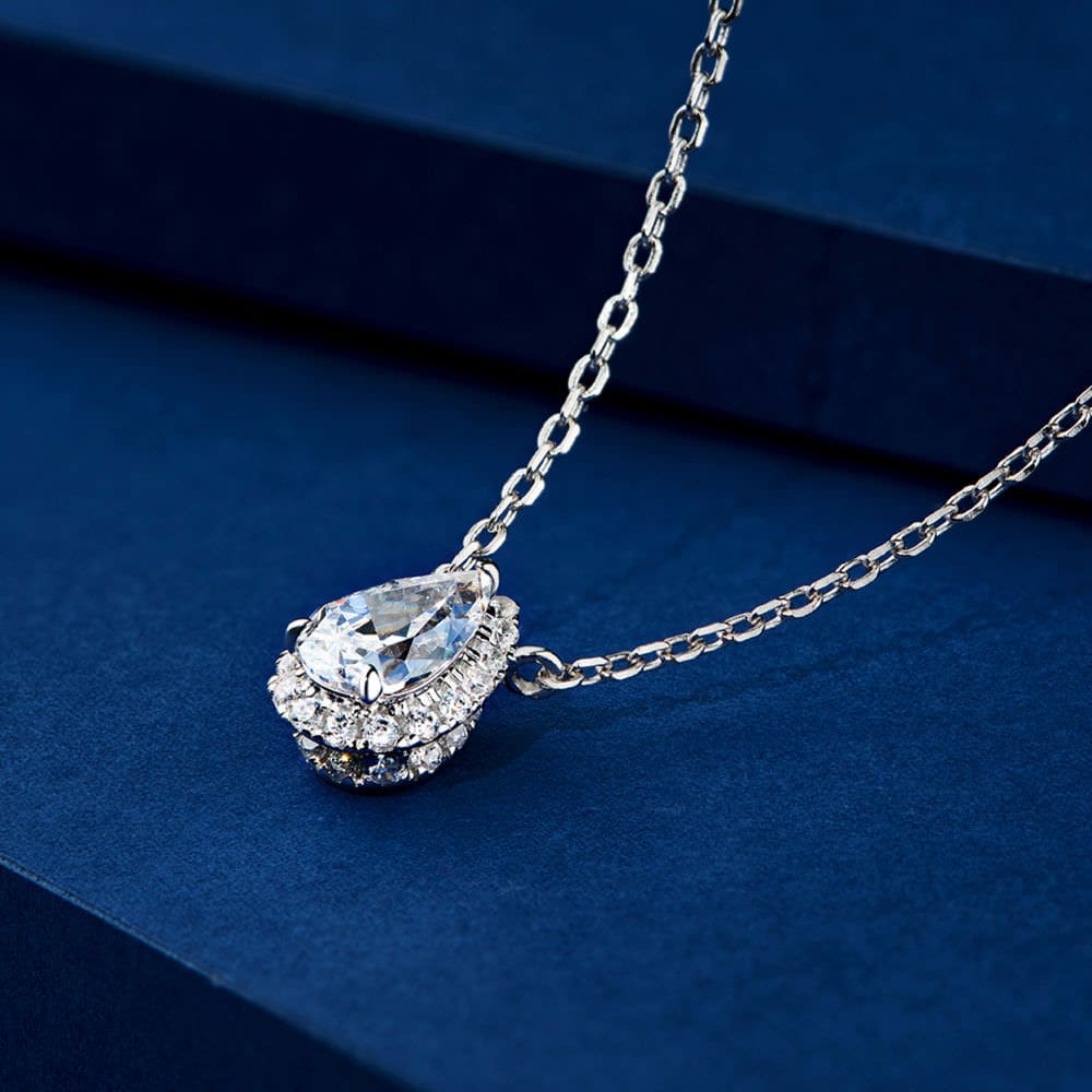 Close-up of a 1.5 carat pear-shaped cubic zirconia pendant necklace with hidden halo setting, worn by a model, showing intricate details and brilliant shine.