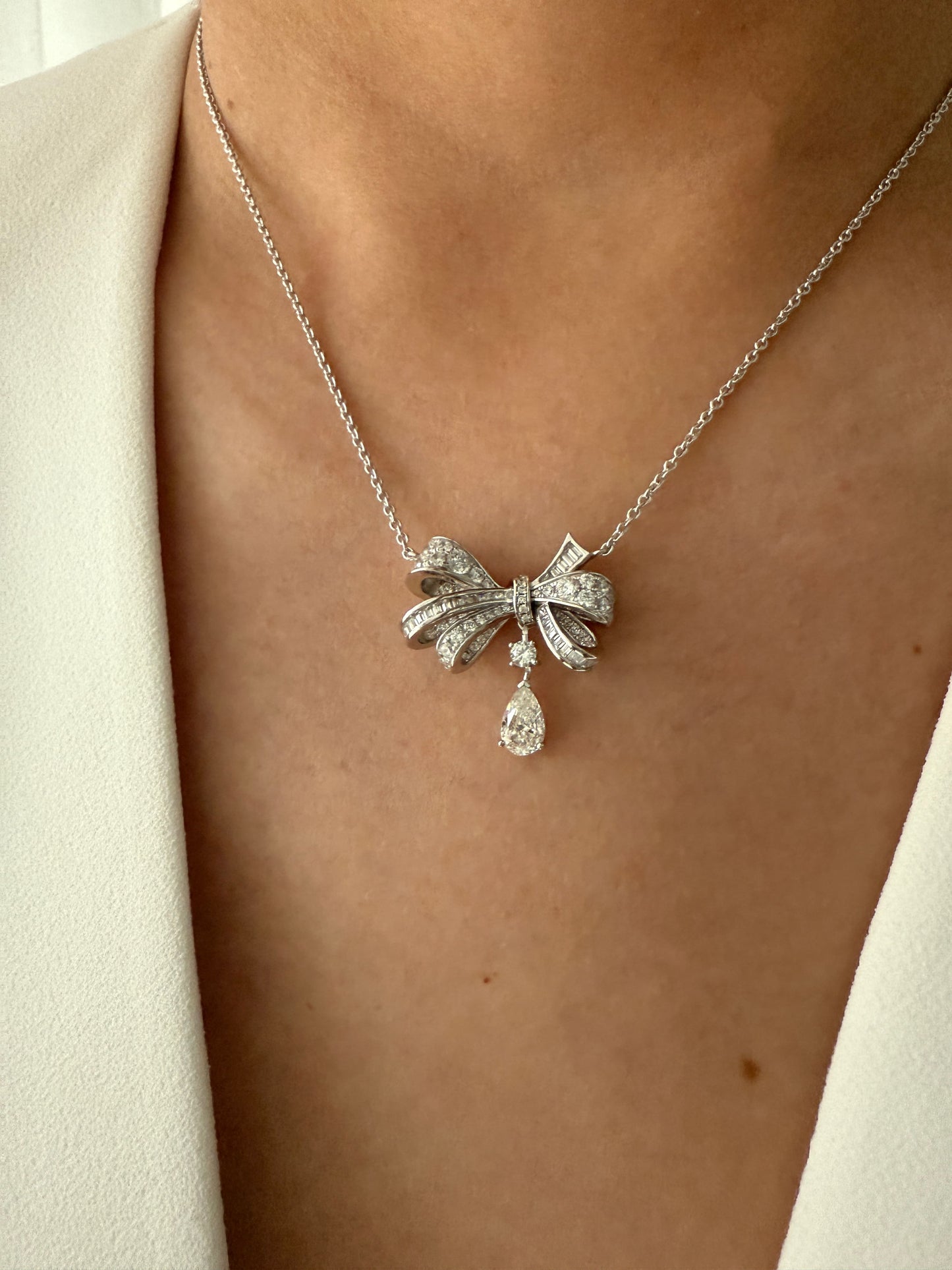 The Belle Bow Necklace in silver, worn by a model as a subtle yet elegant statement piece.